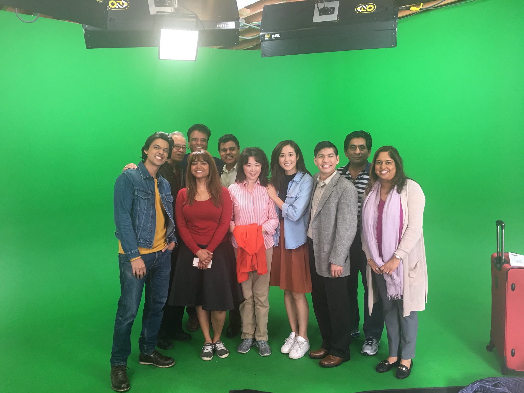 Cast and crew gathered on a green-screen stage after an insurance commercial production